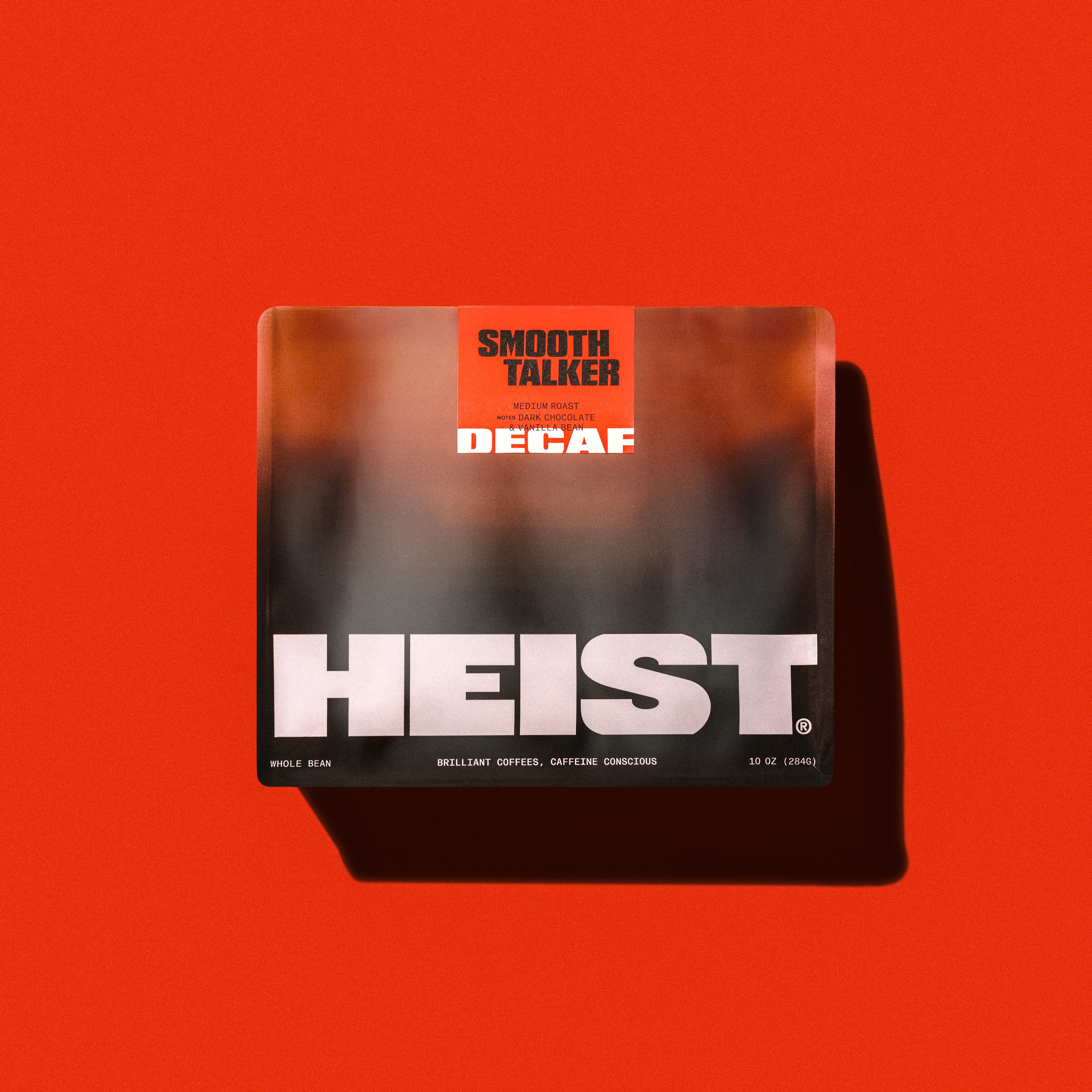 Top-down view of Smooth Talker decaf coffee bag showing HEIST logo and orange SMOOTH TALKER label on a red background