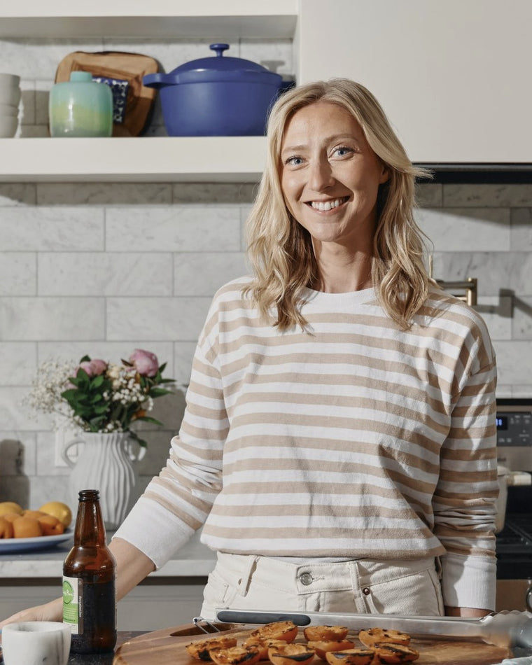 Brita Britnell smiling in a kitchen beside a tray of baked goods