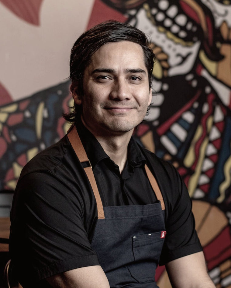 José Contreras wearing a black apron in front of a colorful mural